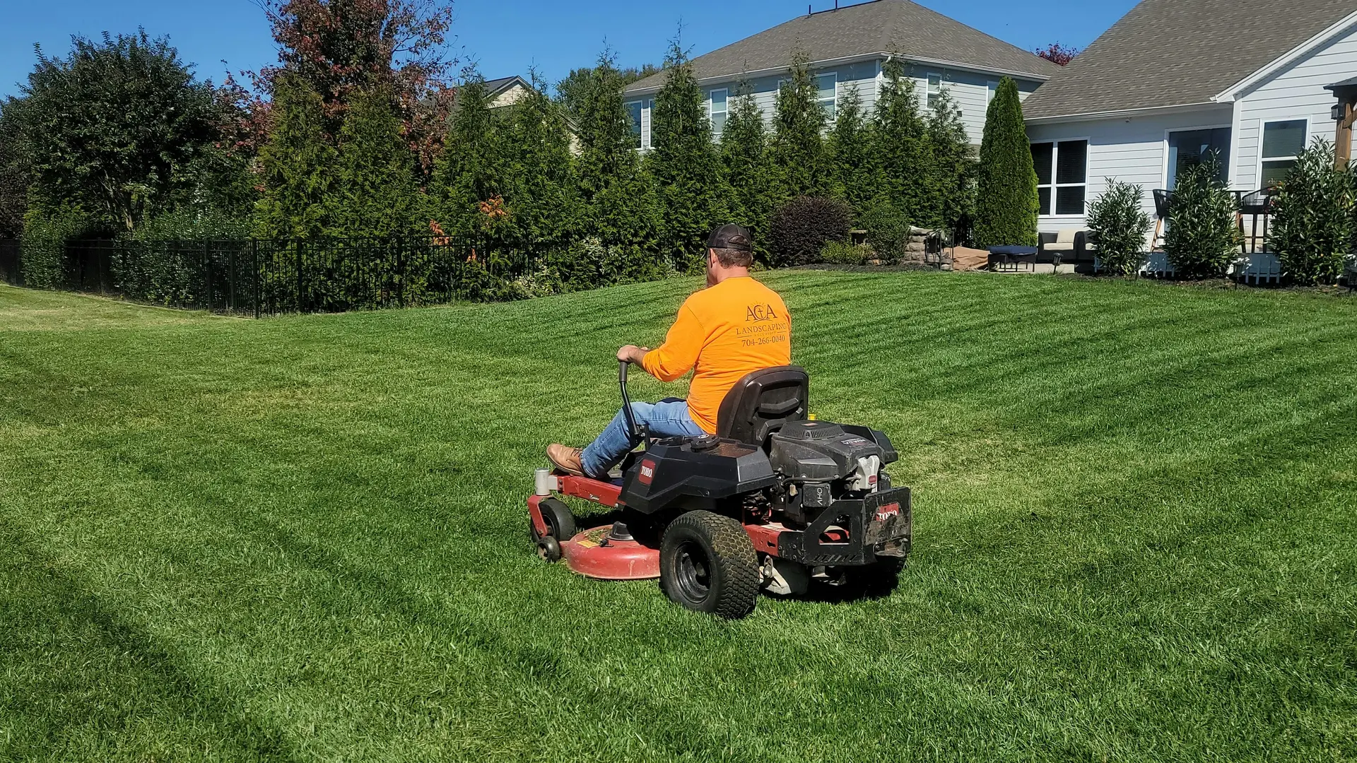Lawn maintenance professional mowing a residential lawn