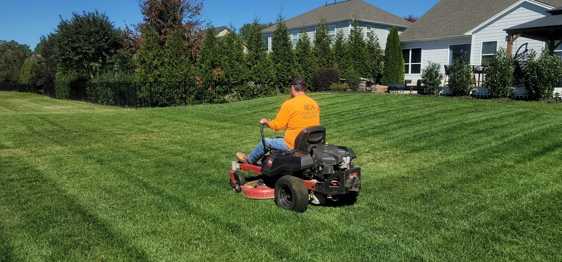 Lawn maintenance professional mowing a residential lawn
